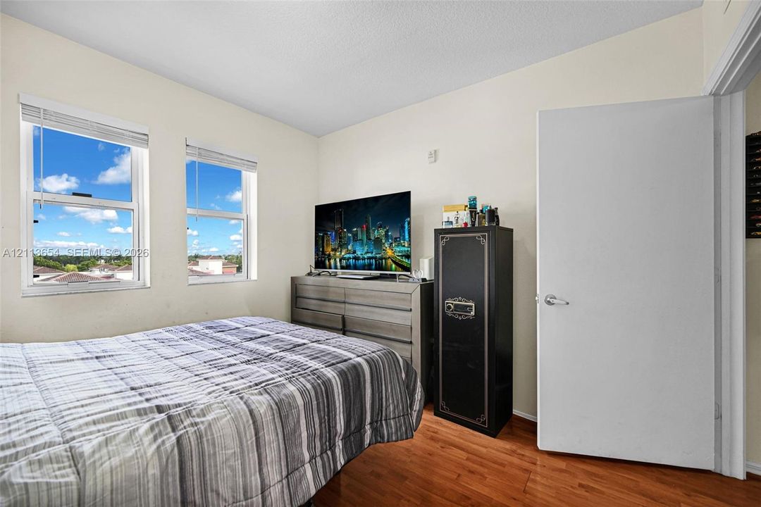 Room featuring wood-finish flooring, two dual-pane windows, and a white interior door with a silver lever handle