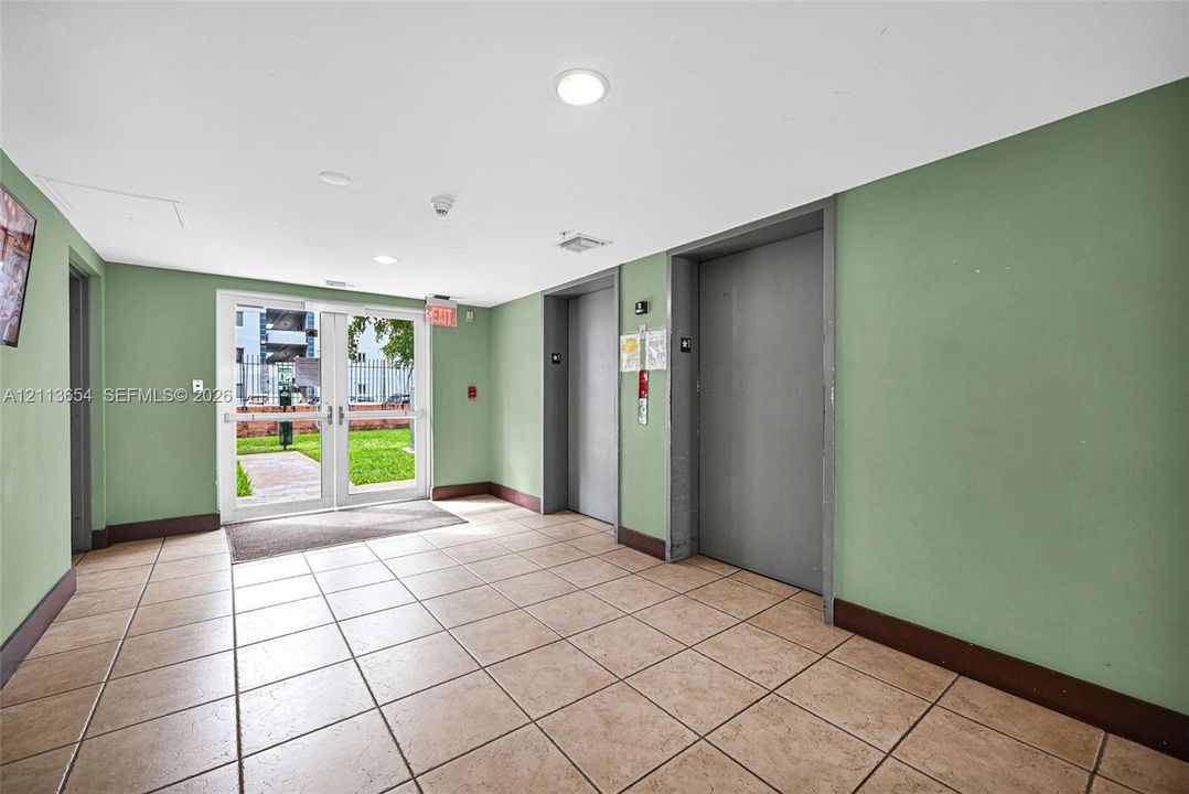 Lobby featuring ceramic tile flooring, dual elevators, and full-glass panel double entry doors