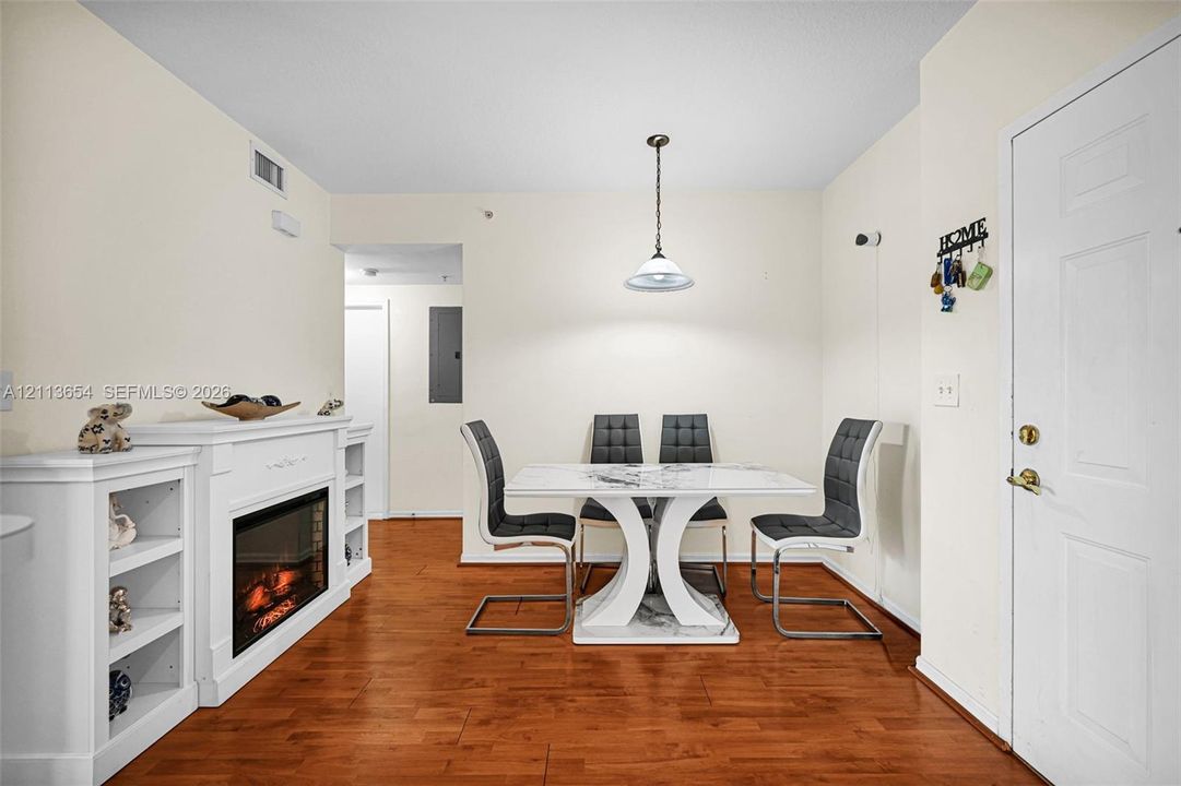 Wood-finish flooring, built-in fireplace with integrated shelving, and pendant lighting