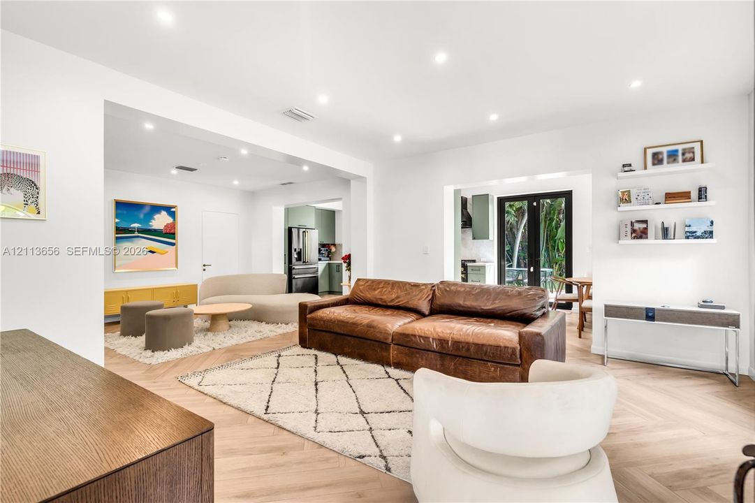 Herringbone-patterned wood-finish flooring, recessed ceiling lighting, and built-in floating wall shelving