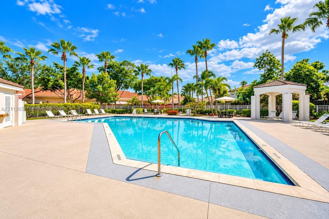 Swimming pool with surrounding concrete deck, metal handrail, and covered pavilion