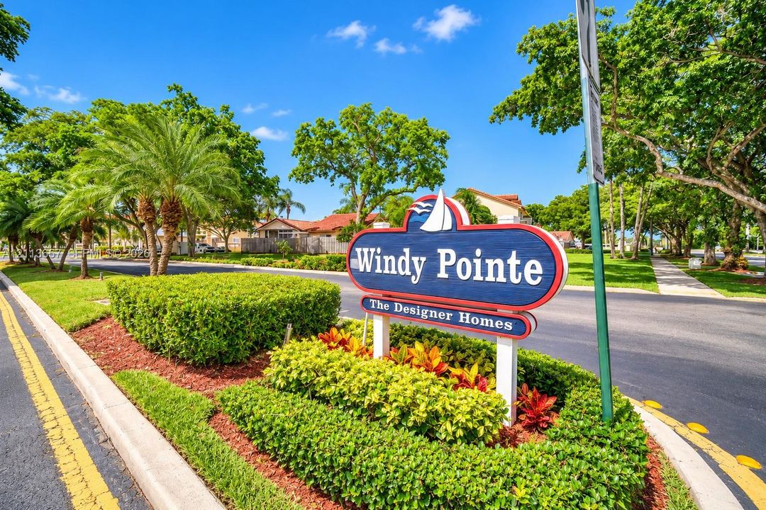 Windy Pointe monument sign featuring professional landscaping, manicured shrubbery, mature trees, and paved roadways
