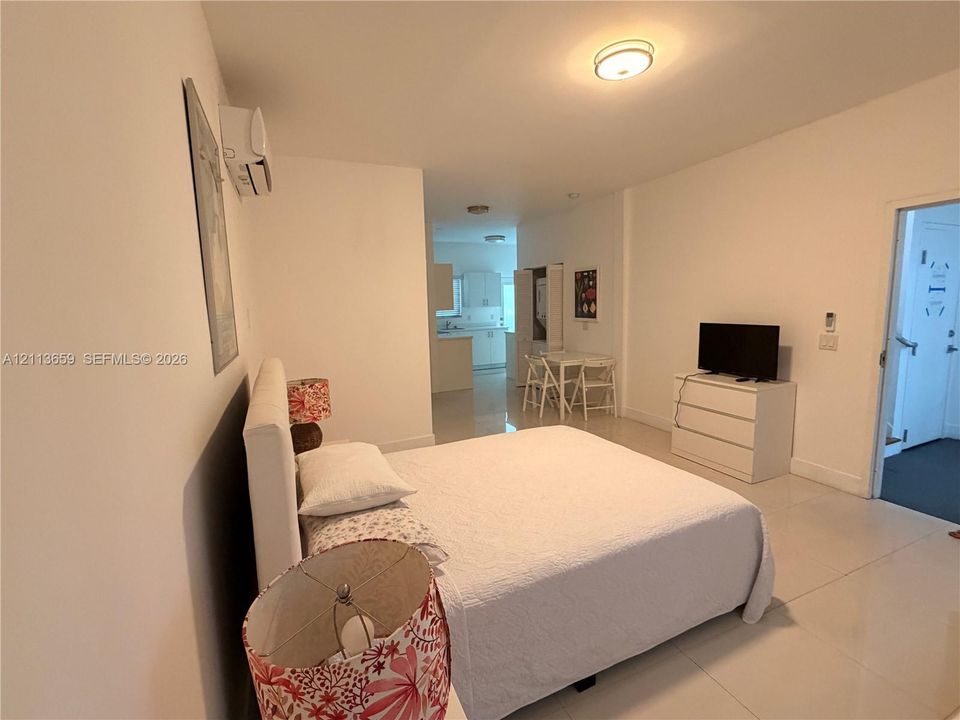 Interior space featuring white tile flooring, ceiling-mounted flush light fixtures, and a wall-mounted ductless air conditioning unit