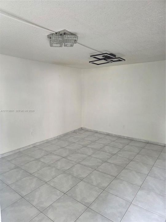 Interior space featuring neutral wall tones, large-format tile flooring, and two modern geometric flush-mount light fixtures