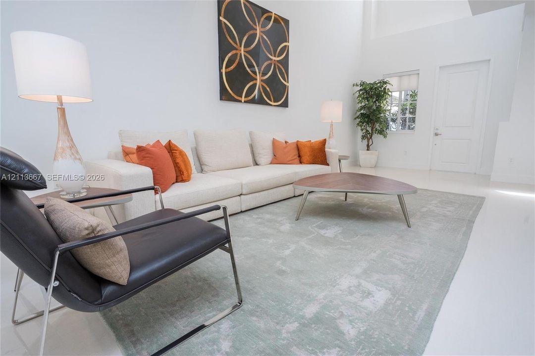 Living area featuring high ceilings, solid surface flooring, and a multi-panel door