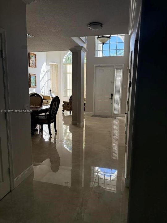 Foyer featuring polished tile flooring, soaring ceilings, decorative columns, arched windows, and a multi-pane glass entry door