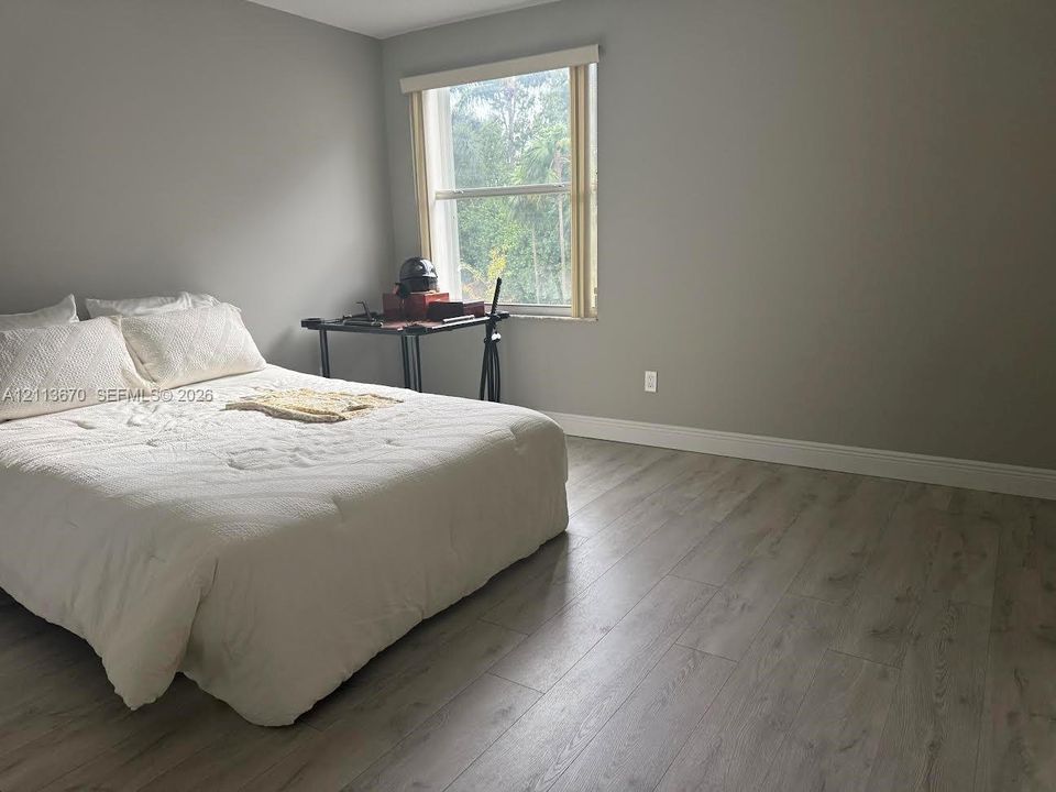 Room featuring wood-finish flooring, neutral wall tones, and a single-hung window with roller shade