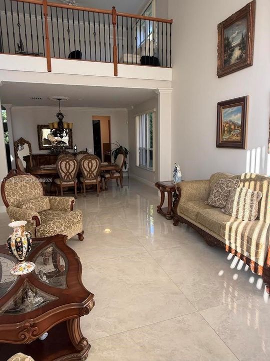 Two-story ceiling height, polished large-format tile flooring, and a mezzanine featuring decorative metal railing