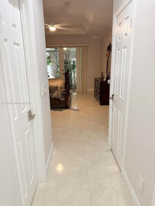 Hallway featuring large-format tile flooring, a tray ceiling, and dual six-panel interior doors
