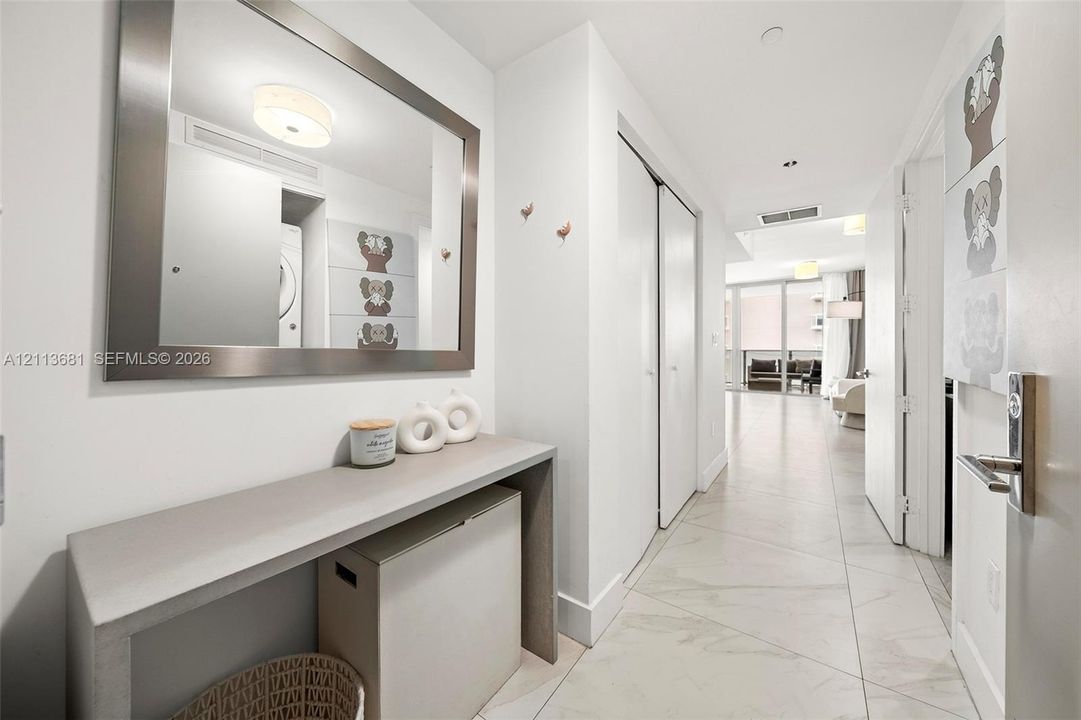 Large-format porcelain tile flooring, built-in console table with a matte finish, oversized wall-mounted mirror with a metallic frame, and flush-mount ceiling lighting