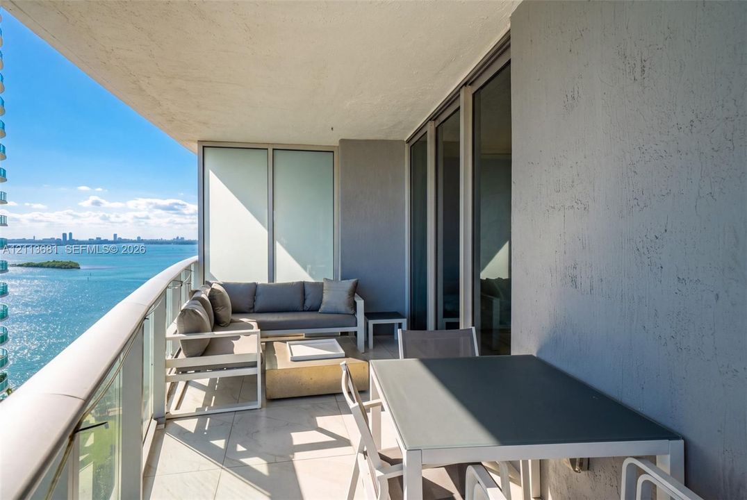 Covered terrace featuring floor-to-ceiling glass doors, a glass-panel railing, and large-format tile flooring