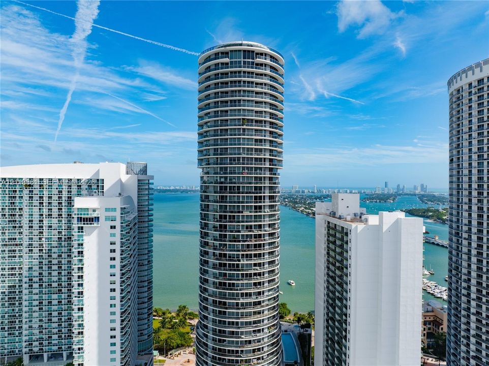 Cylindrical high-rise architecture featuring wraparound balconies and expansive floor-to-ceiling glass windows