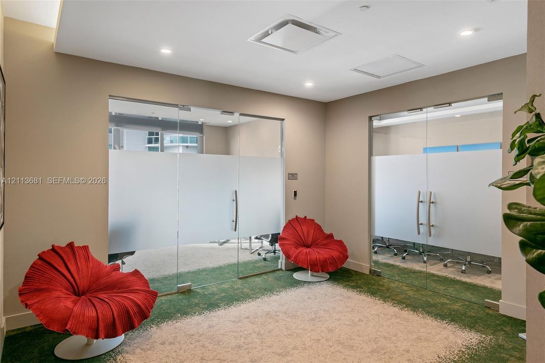 Frameless glass partitions featuring frosted center panels and polished chrome hardware, recessed ceiling lighting, and neutral wall tones