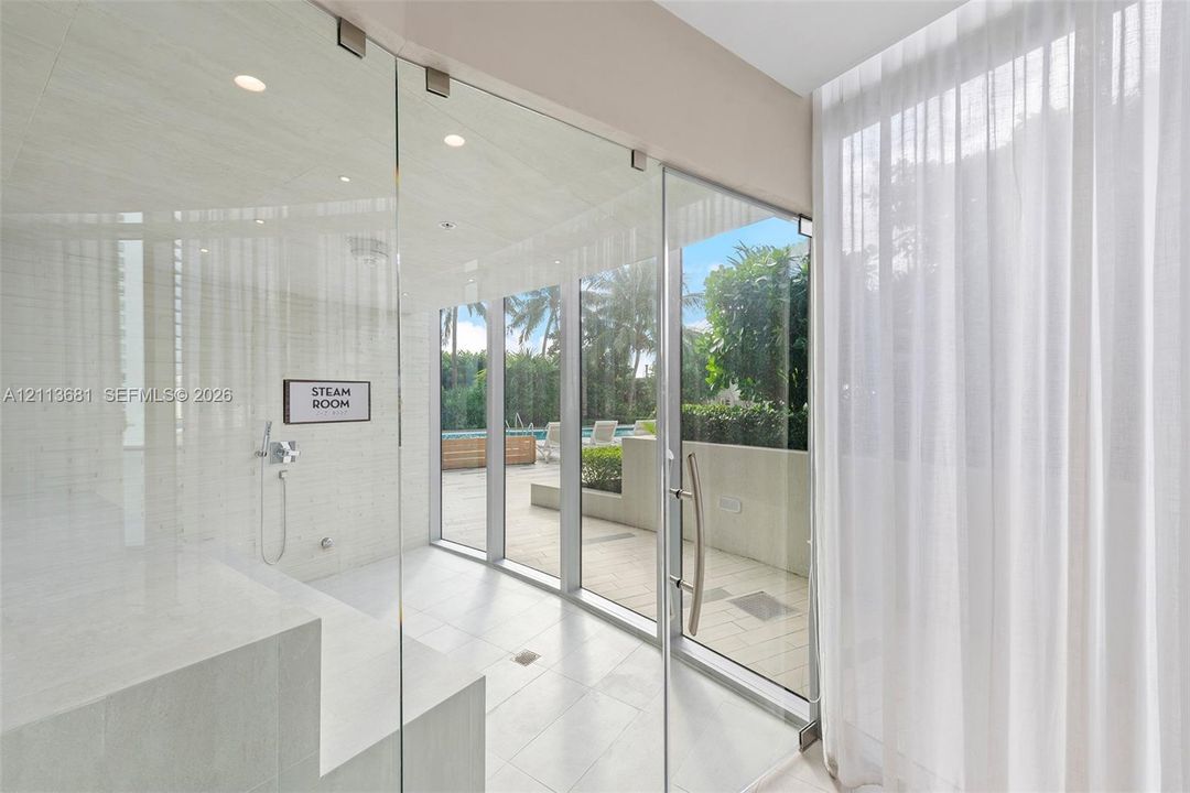 Steam room featuring full-height glass walls, tile flooring, recessed ceiling lighting, and a built-in bench