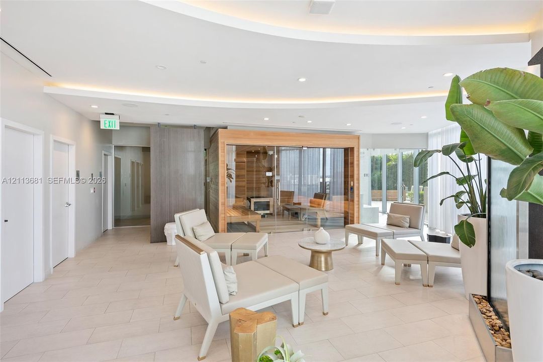 Sauna featuring glass enclosure and wood interior, curved ceiling soffit with recessed cove lighting, large-format tile flooring, and floor-to-ceiling windows