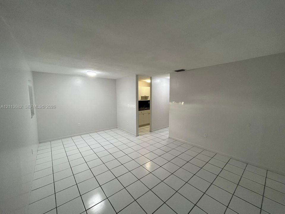 Interior space featuring white tile flooring, neutral wall paint, and surface-mounted ceiling light fixtures