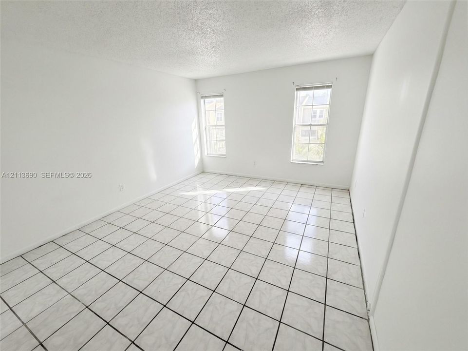 Interior room featuring white-painted walls, square ceramic tile flooring, and two windows with horizontal blinds