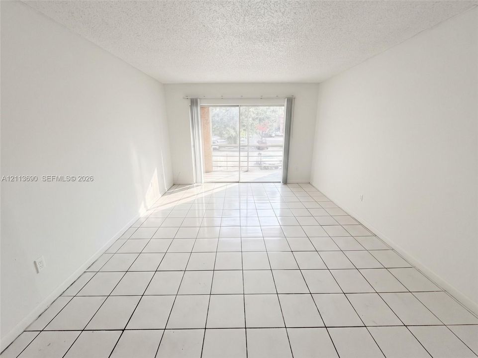 Room featuring white tile flooring and large sliding glass doors