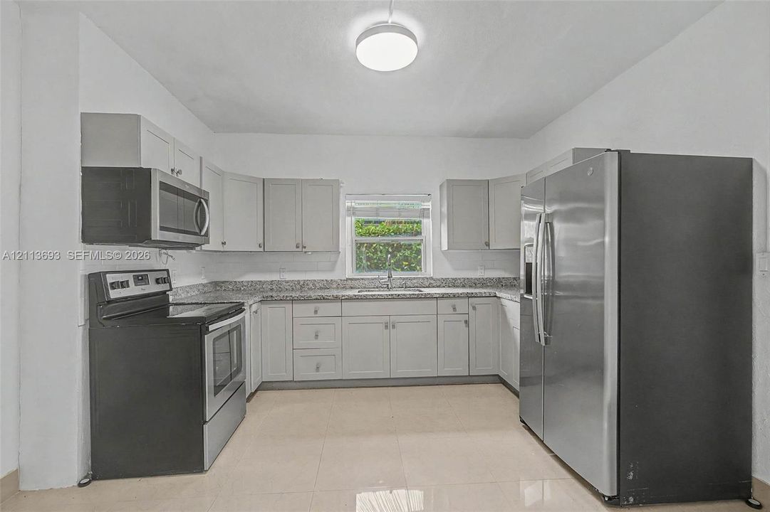 Kitchen featuring light gray cabinetry, stone-finish countertops, stainless steel appliances, and tile flooring