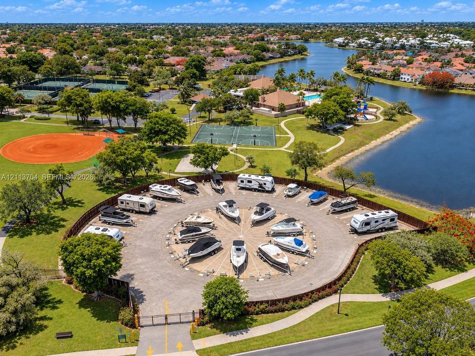 Gated circular storage area featuring paved parking pads for watercraft and recreational vehicles, enclosed by perimeter fencing
