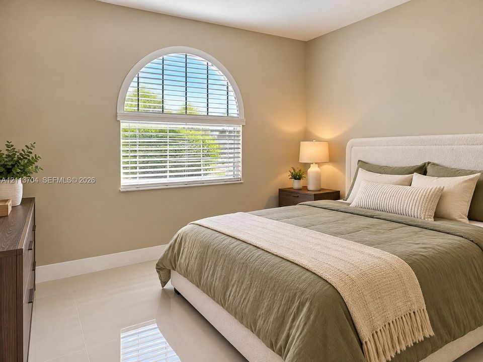 Room featuring neutral wall paint, polished tile flooring, and an arched window with horizontal blinds