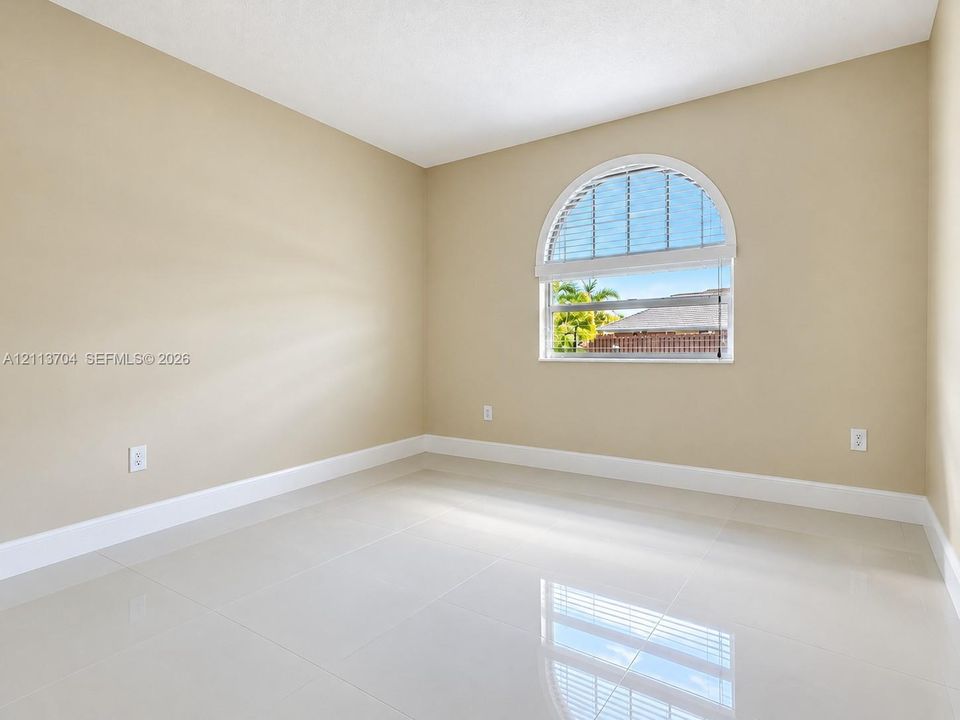 Neutral-toned interior featuring large-format tile flooring and an arched window with an integrated blind