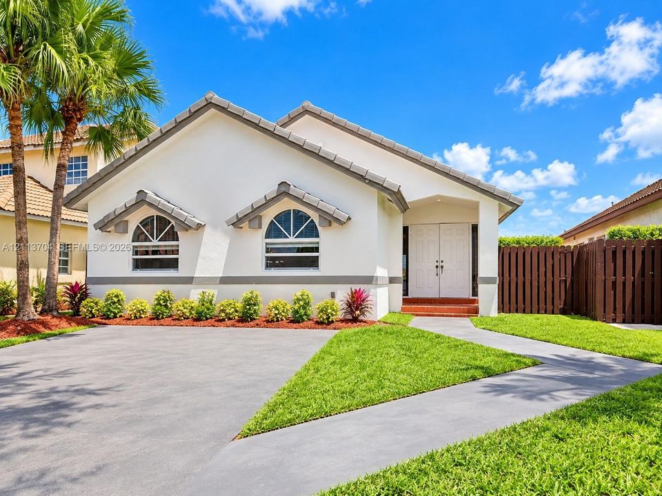 Single-story residence featuring a tile roof, stucco exterior, arched windows, dual-entry doors, and a concrete driveway