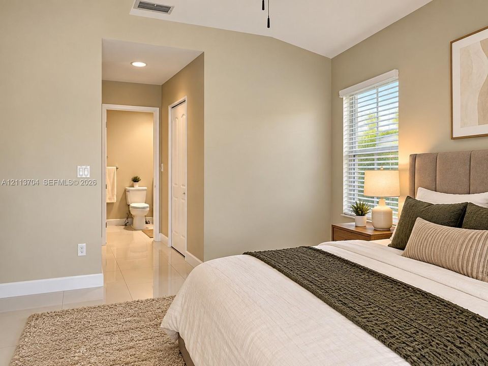 Neutral-toned room featuring high-gloss tile flooring, vaulted ceiling, and window with built-in blinds