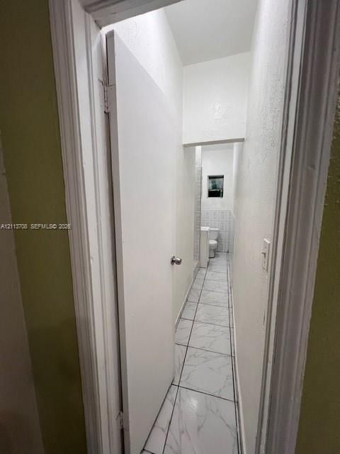 Neutral-toned tiled flooring, interior swinging door with metallic hardware, and white wall finishes