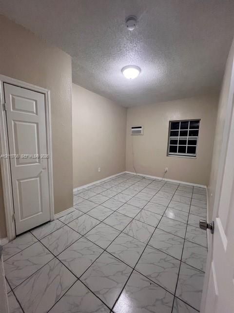 Room featuring white tile flooring with gray veining, a six-panel interior door, a multi-pane window, and a wall-mounted climate control unit
