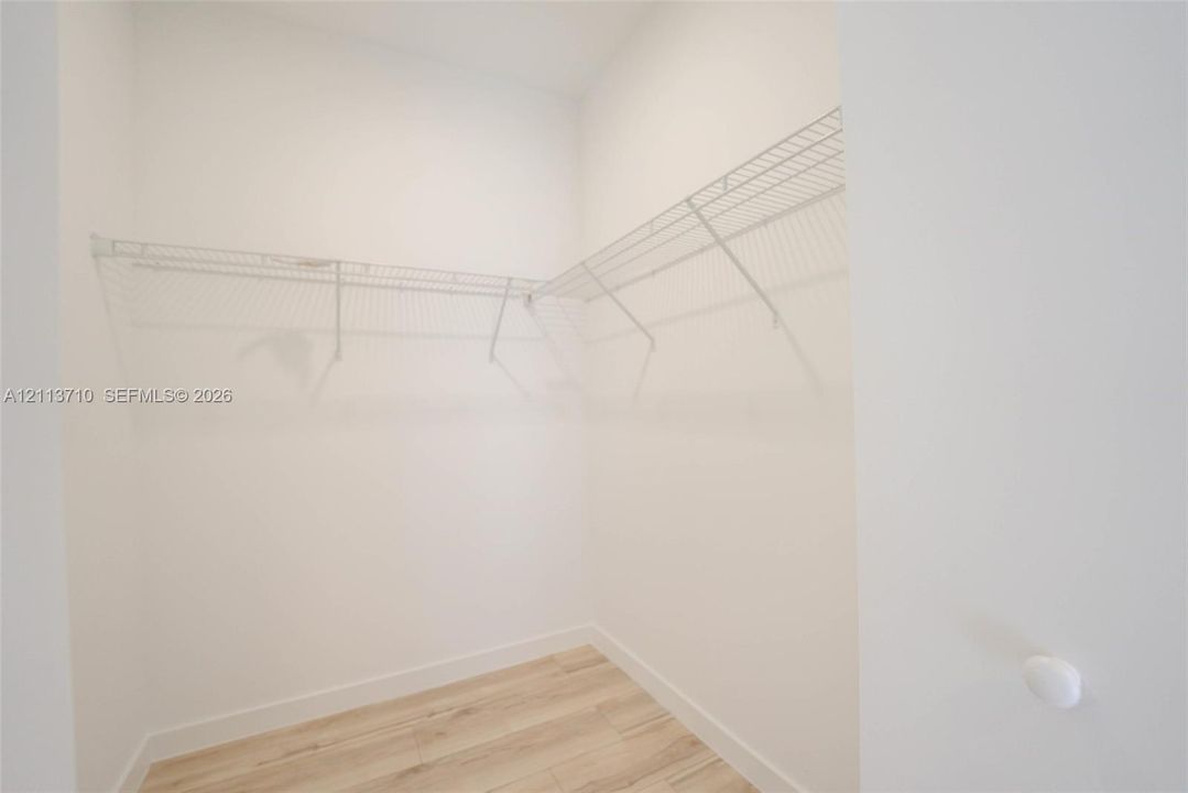 Walk-in storage space featuring wood-finish flooring and white wire shelving
