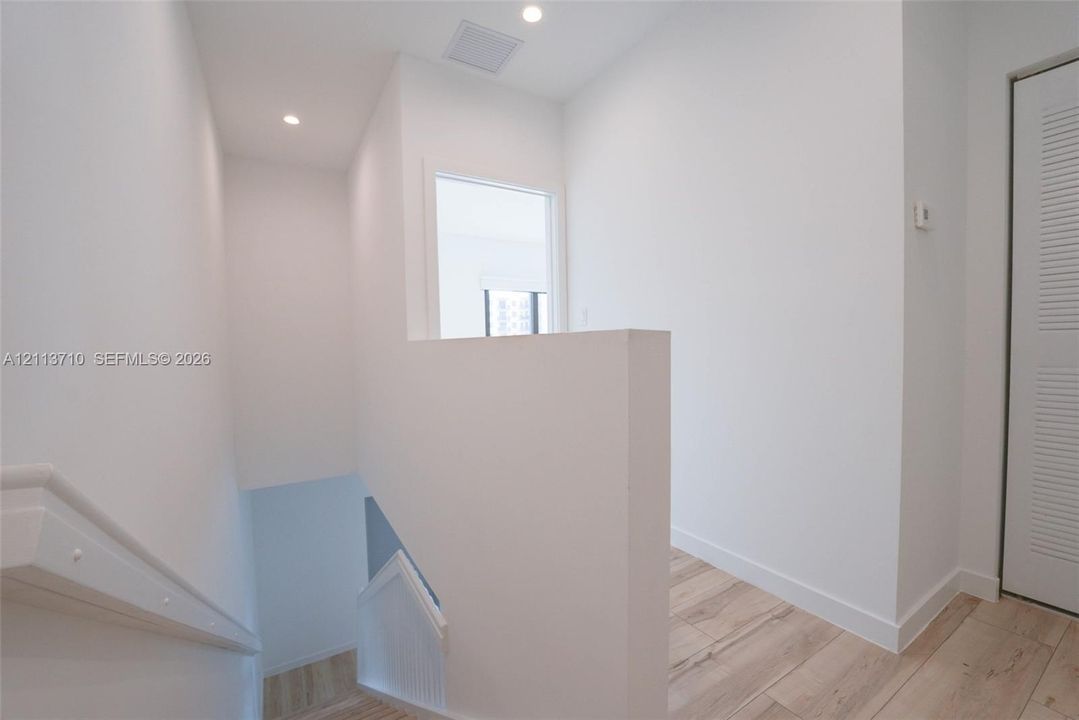 Interior landing featuring wood-finish flooring, recessed lighting, and louvered closet doors