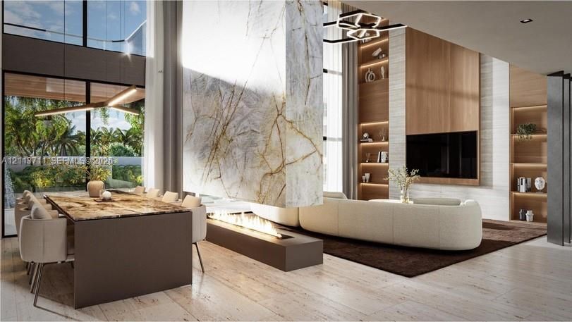 Double-height ceilings, stone-clad dual-sided fireplace, floor-to-ceiling windows, custom built-in wood shelving, and stone flooring