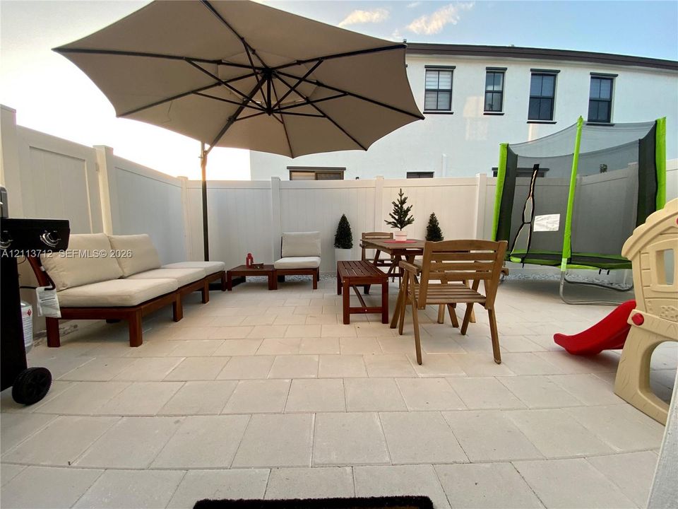 Private patio featuring light-toned concrete pavers enclosed by a white vinyl privacy fence
