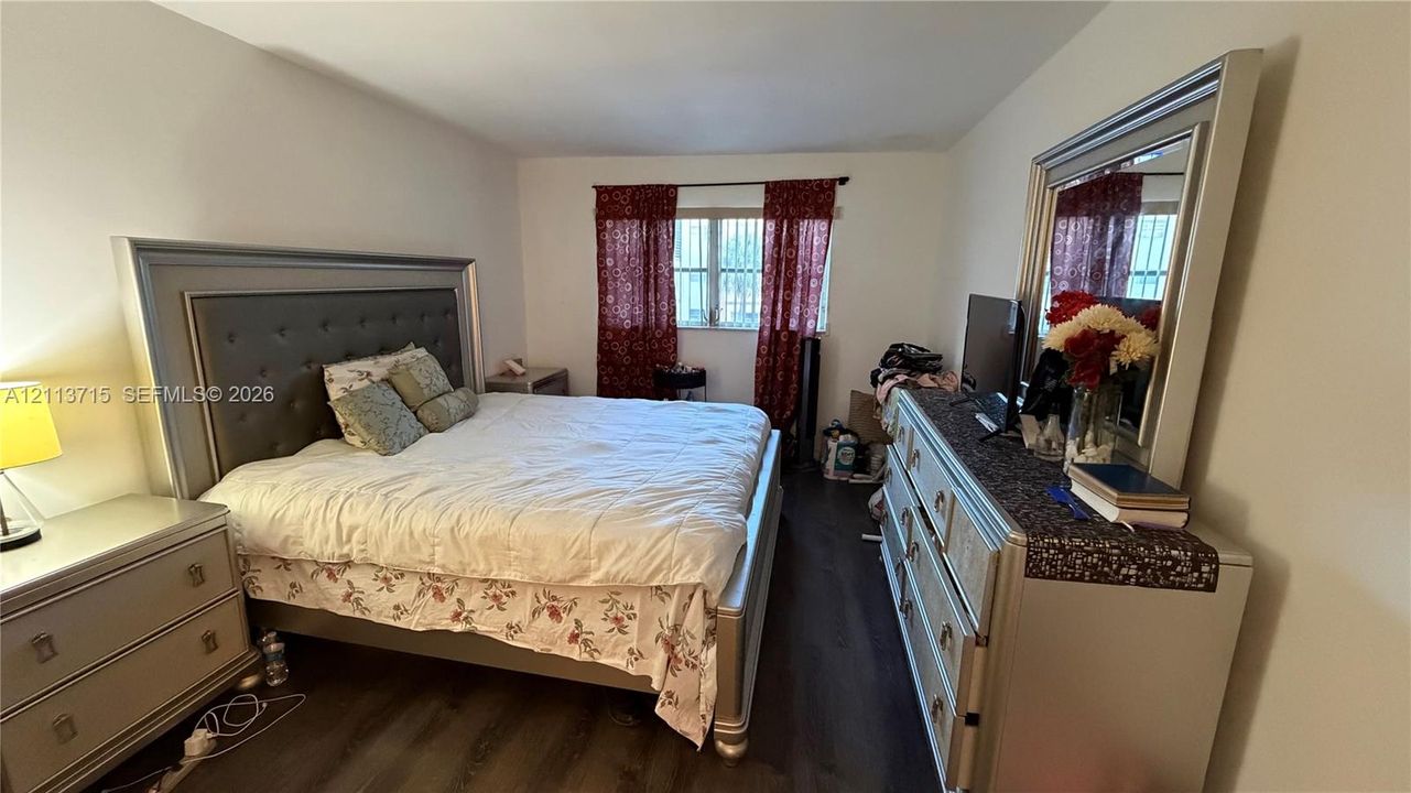 Room featuring dark wood-finish flooring and a window with security bars