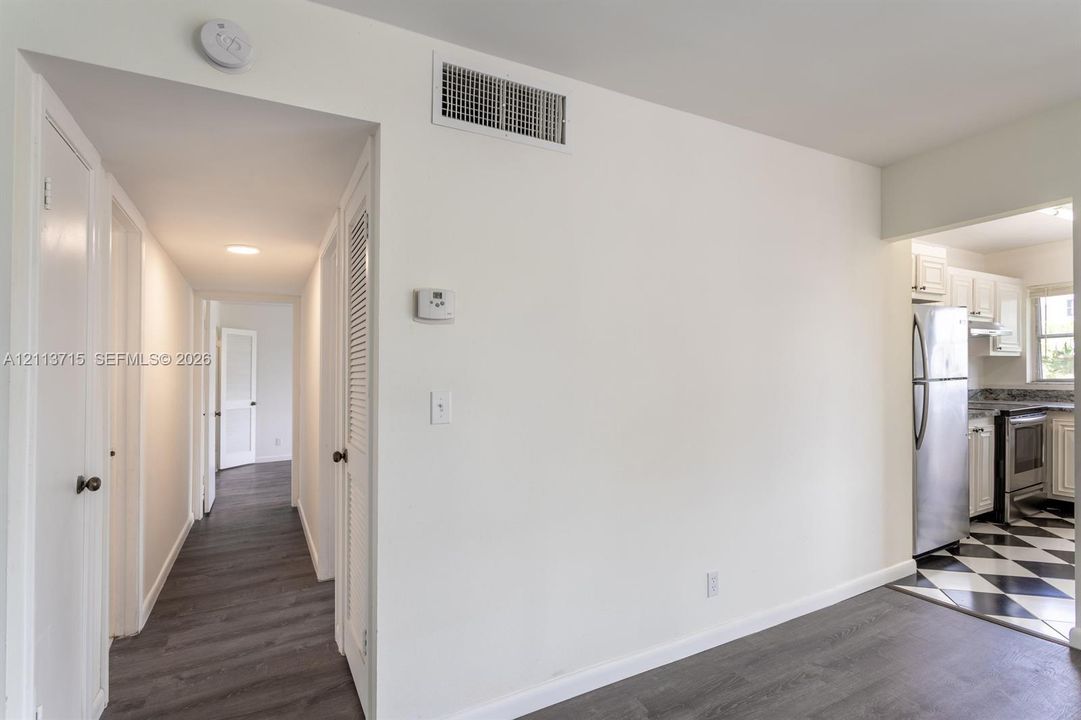 Interior featuring wood-finish flooring, white cabinetry, stainless steel refrigerator, stainless steel range, and monochrome tile flooring