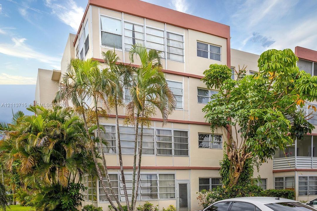 Multi-story residential building featuring mid-century architectural styling, horizontal banding, and extensive window groupings