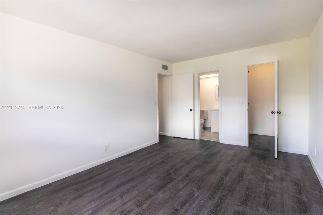 Room featuring neutral wall paint, wood-finish flooring, and solid-core interior doors
