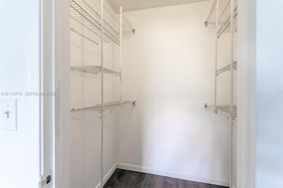 Storage area featuring white wire shelving units and wood-finish flooring