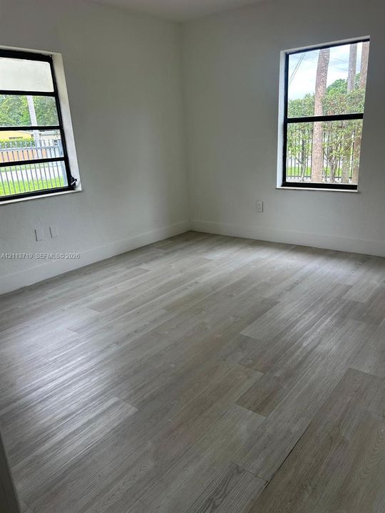 Interior room featuring wood-finish flooring, neutral walls, and two windows with black frames