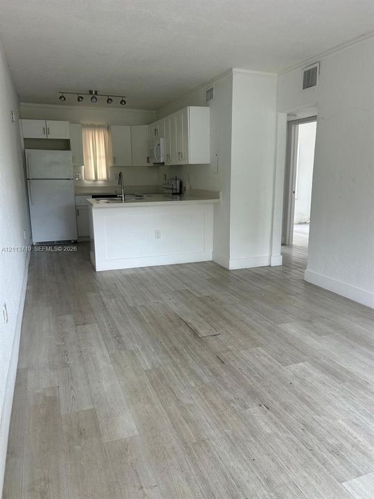 Kitchen featuring wood-finish flooring, white cabinetry, a peninsula counter, and track lighting