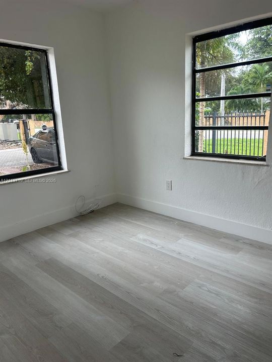 Light-filled room featuring wood-finish flooring and two windows with black-frame horizontal pane configurations