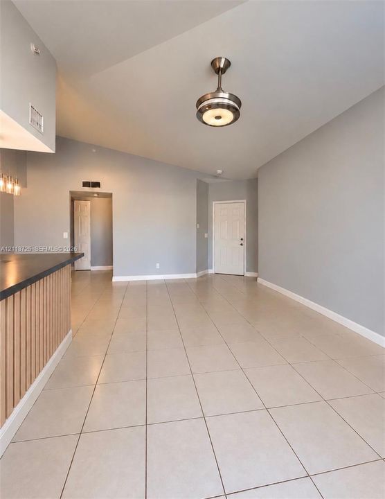 Vaulted ceilings, large-format tile flooring, a breakfast bar featuring vertical wood-slat detailing, and a contemporary semi-flush mount light fixture