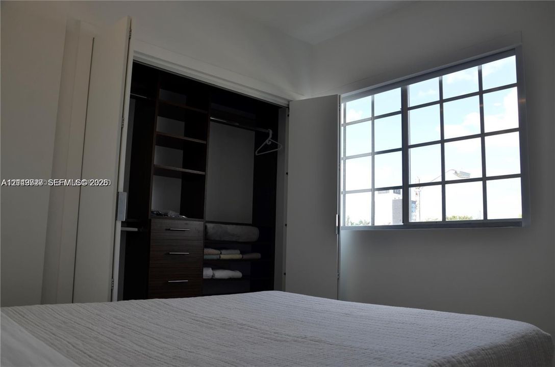 Custom built-in closet system featuring dark wood-finish cabinetry, integrated shelving, and multi-drawer storage, paired with a multi-pane grid window