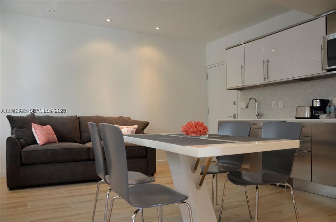 Kitchen area featuring high-gloss cabinetry, stainless steel lower cabinets, recessed lighting, and wood-finish flooring