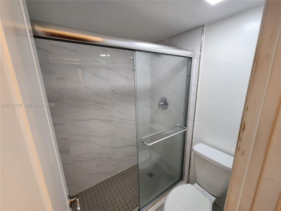 Pass-through serving window featuring stone-composite countertops, stainless steel sink with a high-arch faucet, and wood-finish flooring