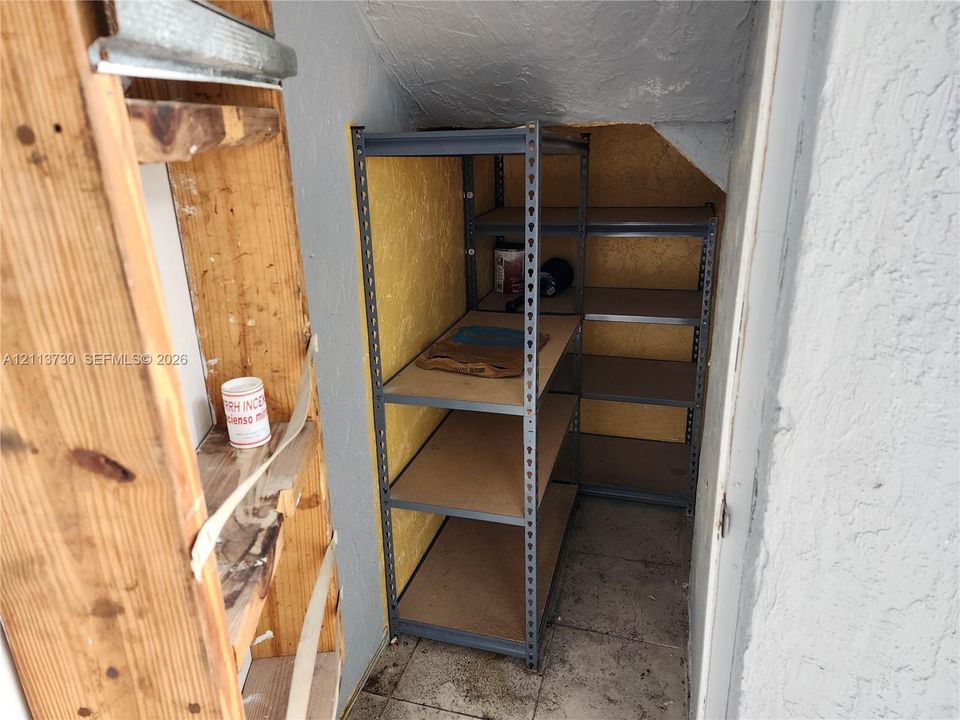 Reach-in closet featuring white paneled bifold doors, wood-finish flooring, and multi-tier wire shelving