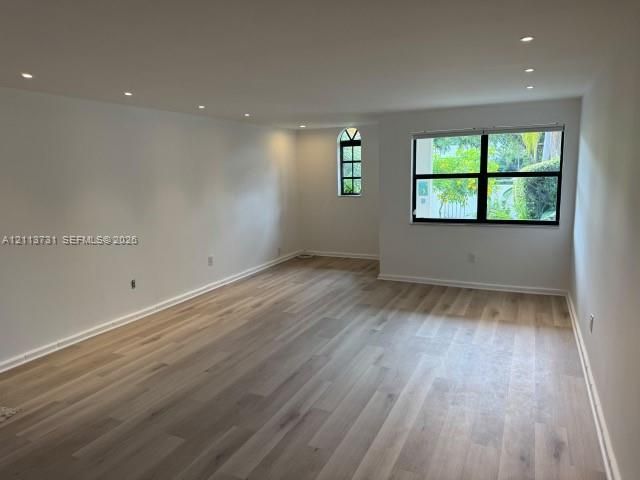 Interior space featuring wood-finish flooring, recessed lighting, and windows with black frames, including an arched accent window