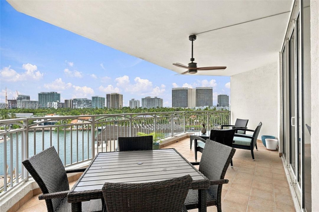 Covered balcony featuring tile flooring, ceiling fan, and metal railings overlooking the waterway