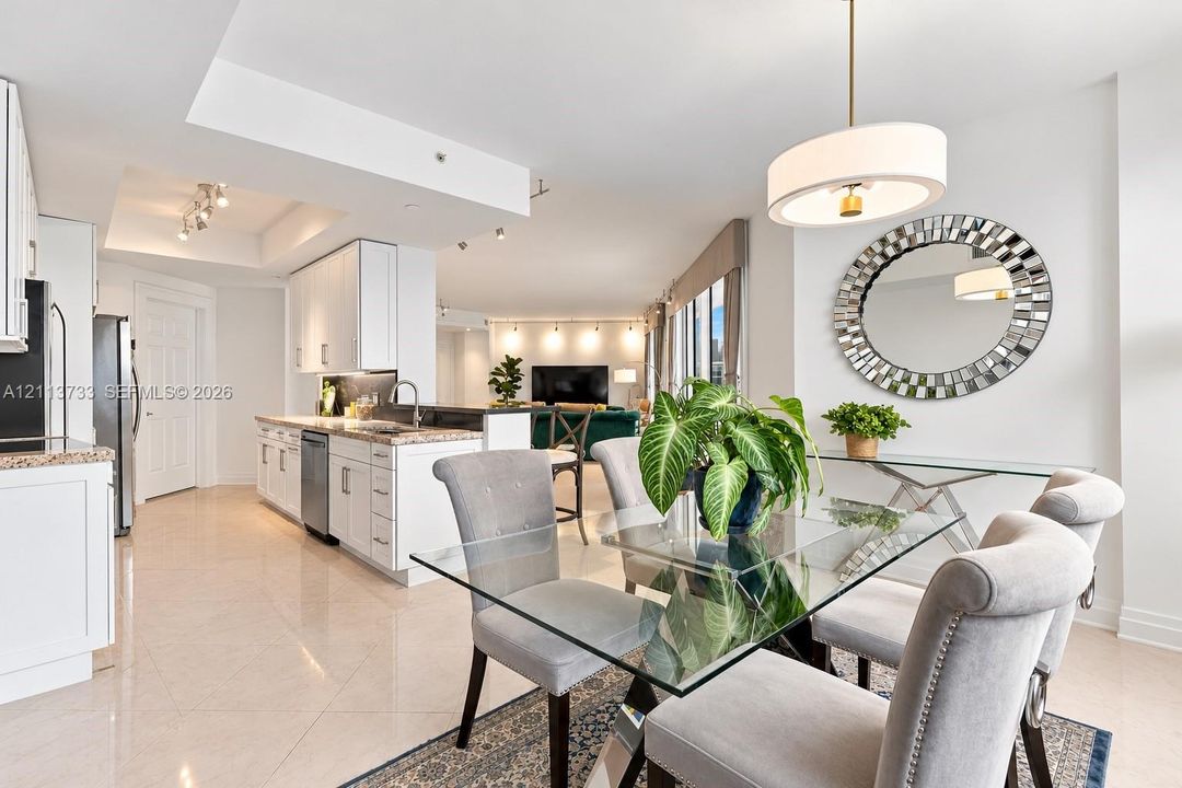 Kitchen featuring white cabinetry, stone-finish countertops, and stainless steel appliances, complemented by light tile flooring and a suspended drum pendant light
